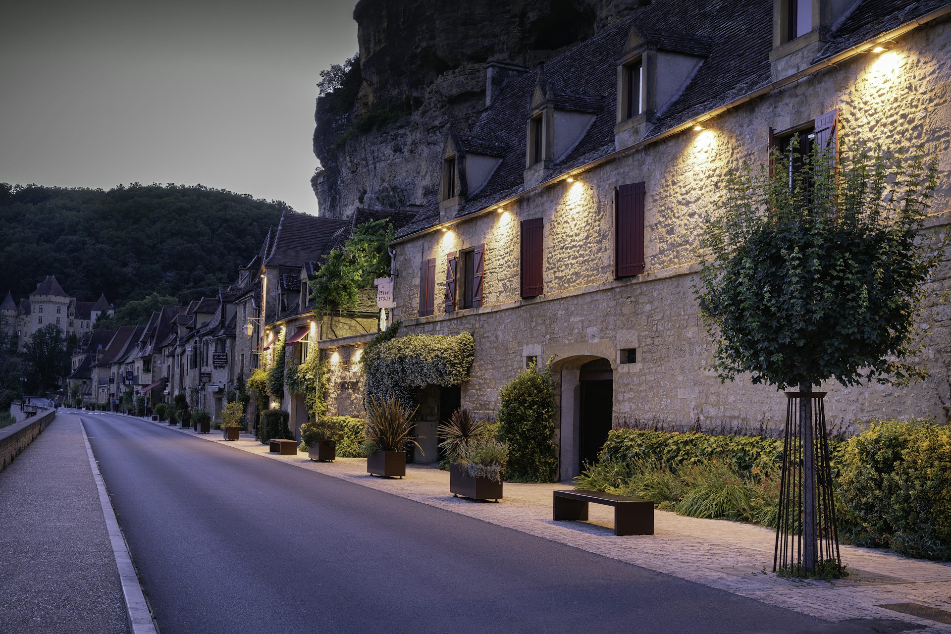 Rue paisible de La Roque-Gageac, village de Dordogne, à la tombée du soir — façades en pierre et fenêtres éclairées